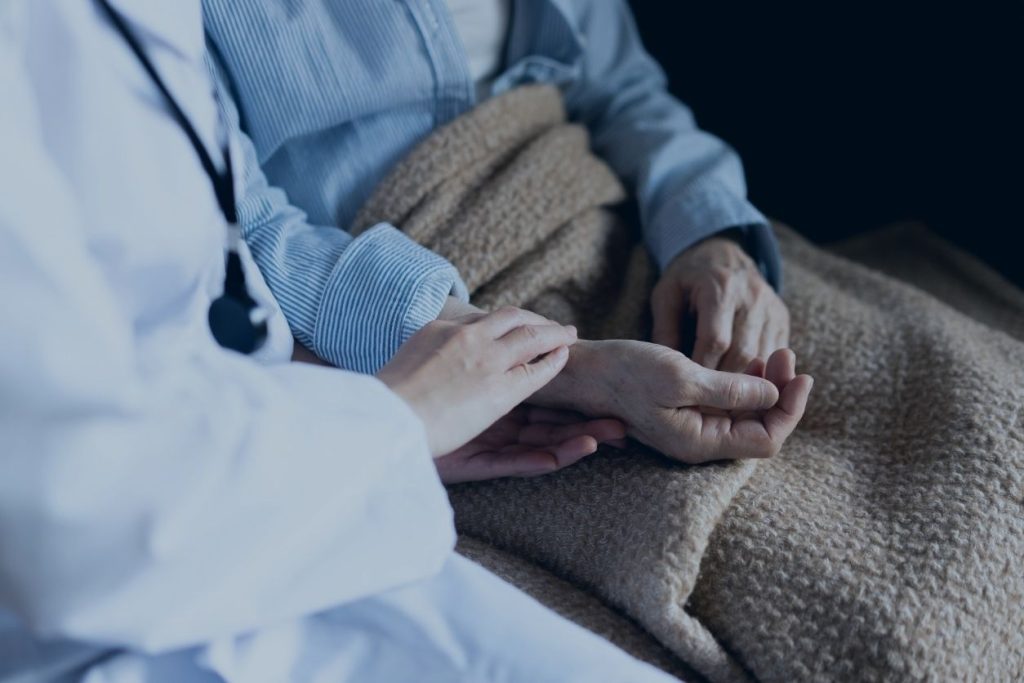 Doctor holding hand of elderly person illustrating Palliative Care