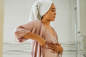 Aging woman looking in mirror for breast self-exam